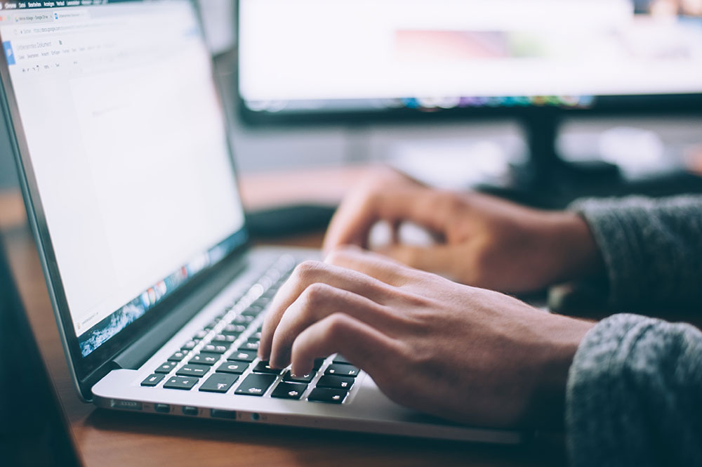 hands typing into a spreadsheet on a Macbook Pro